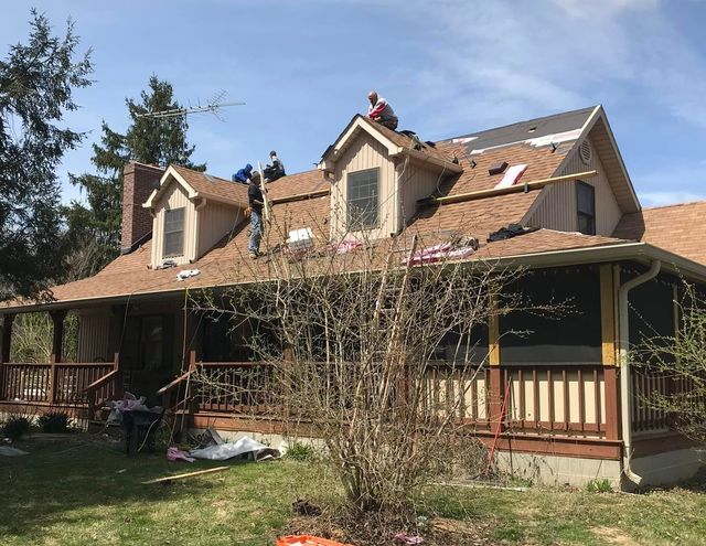 A group of people are working on the roof of a house.