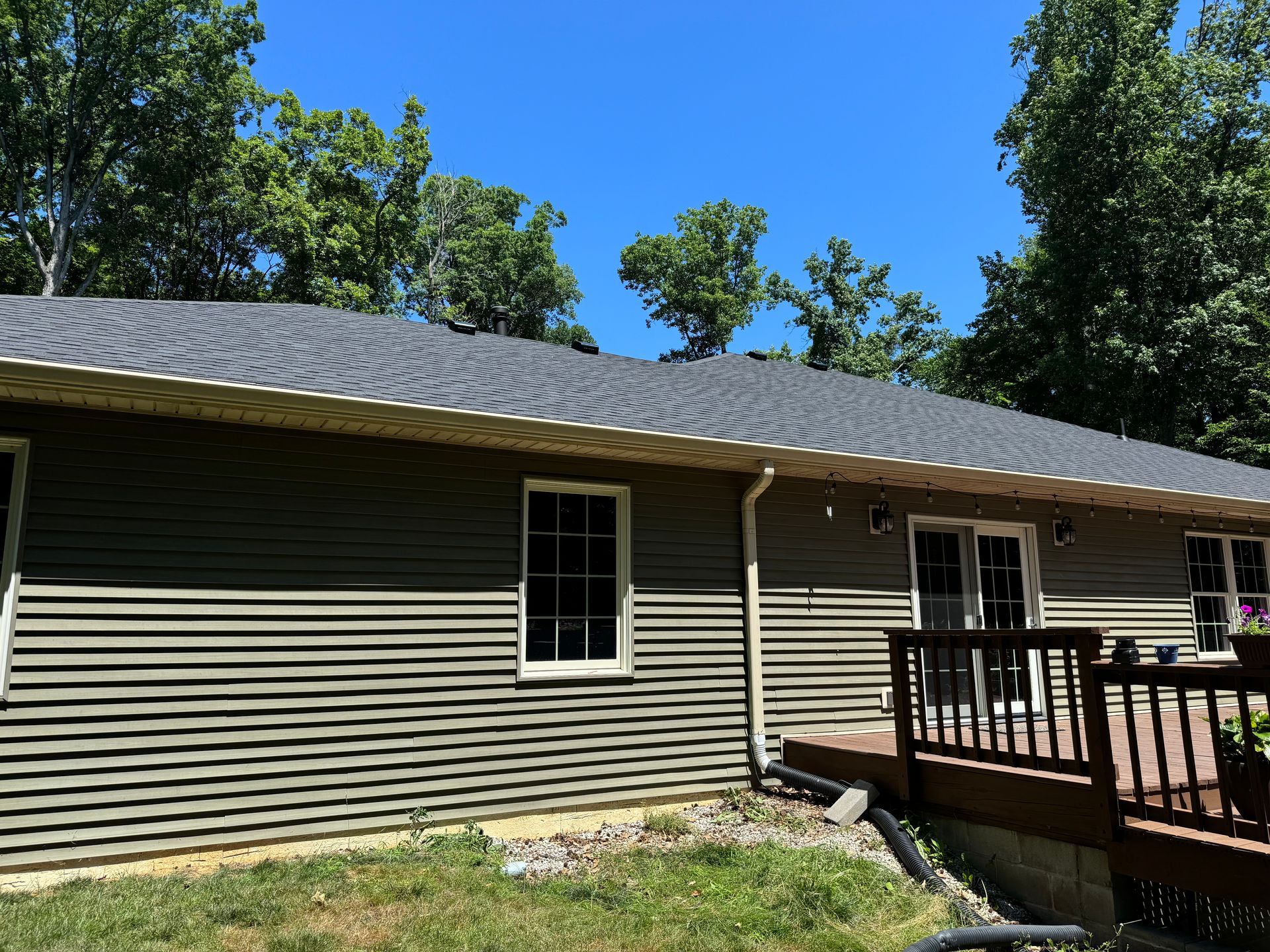 The back of a house with a deck and trees in the background.