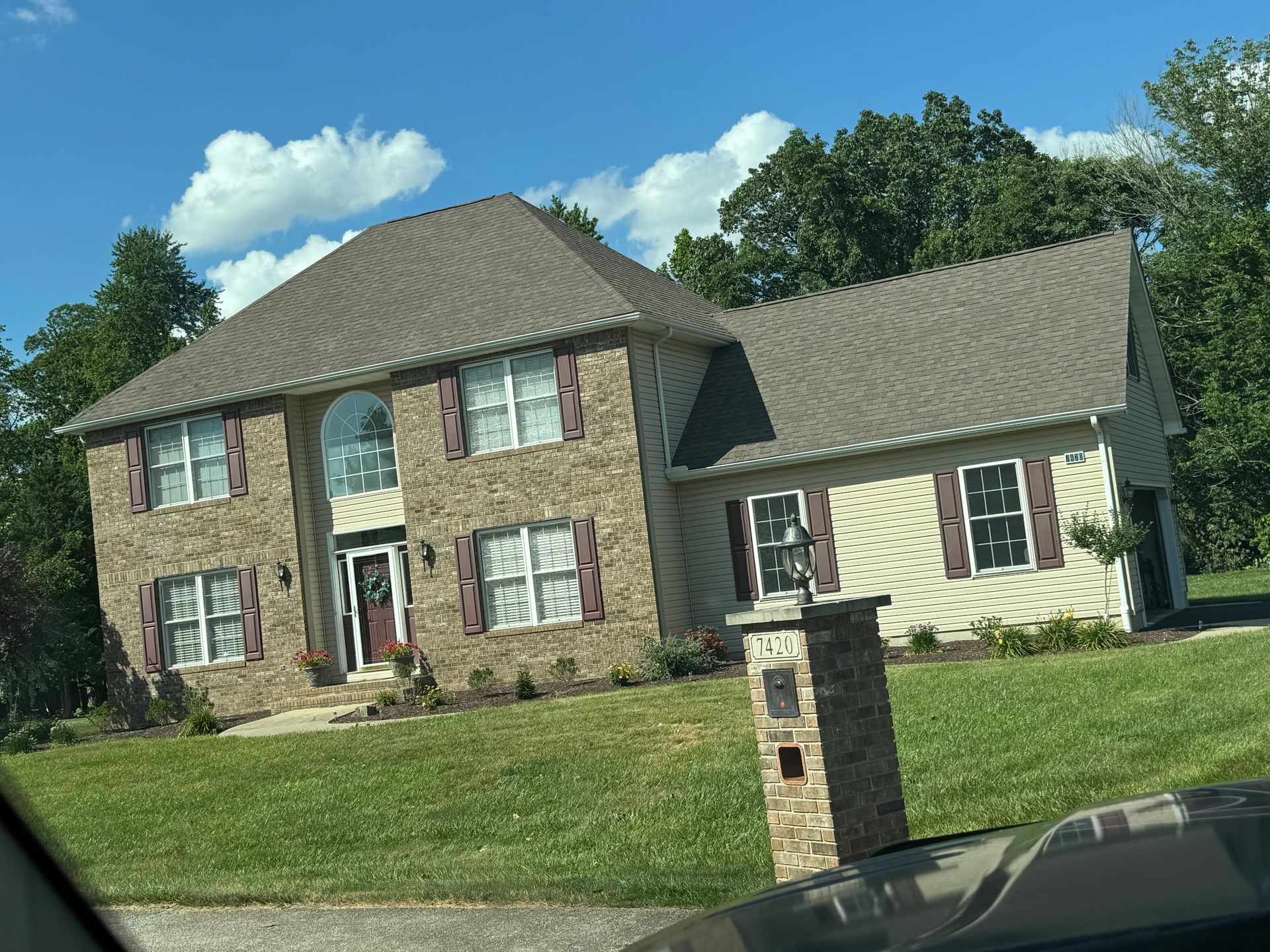 A large brick house with a large lawn in front of it.