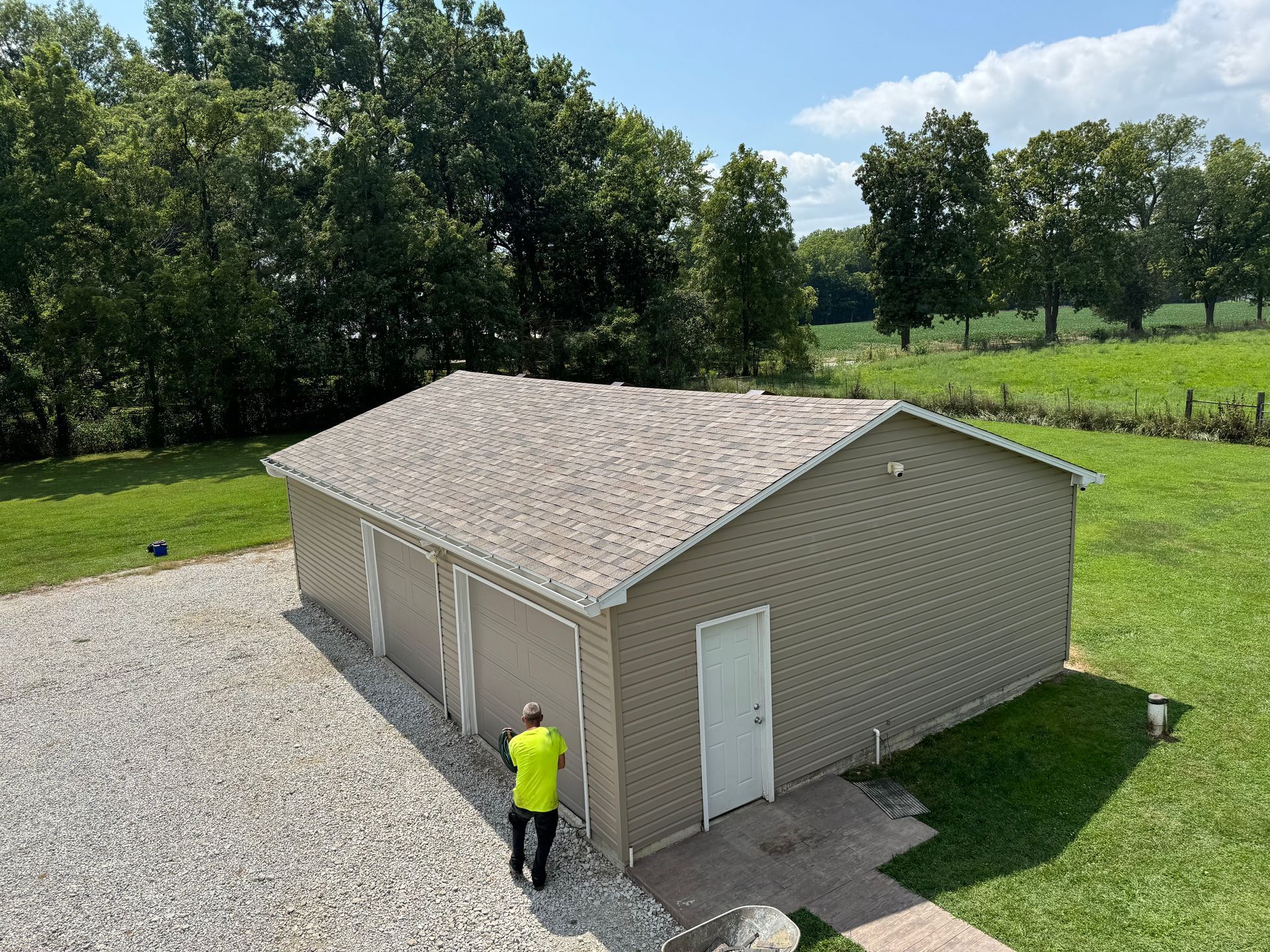 A man in a yellow shirt is standing in front of a garage.