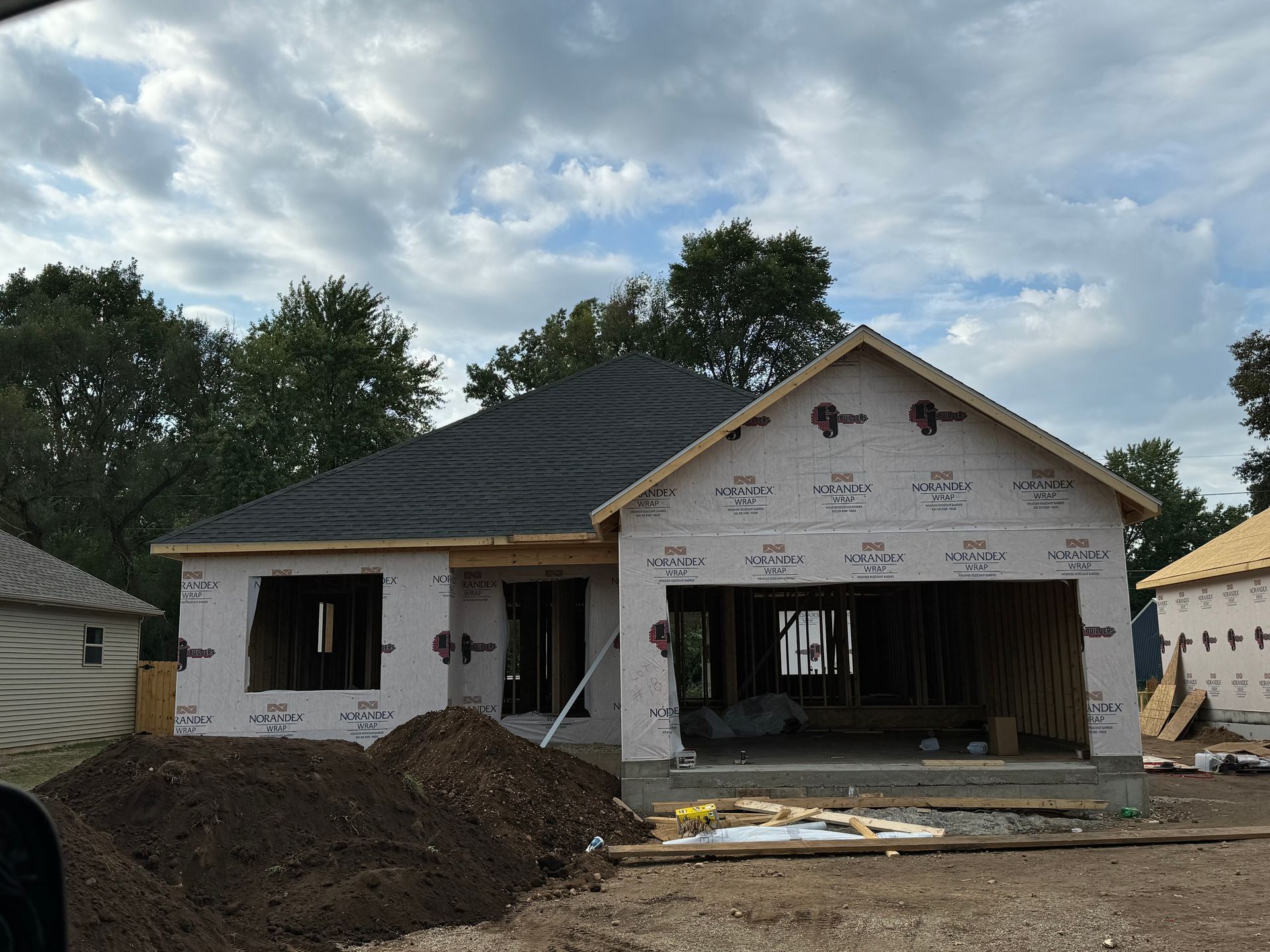 A house under construction with a large pile of dirt in front of it