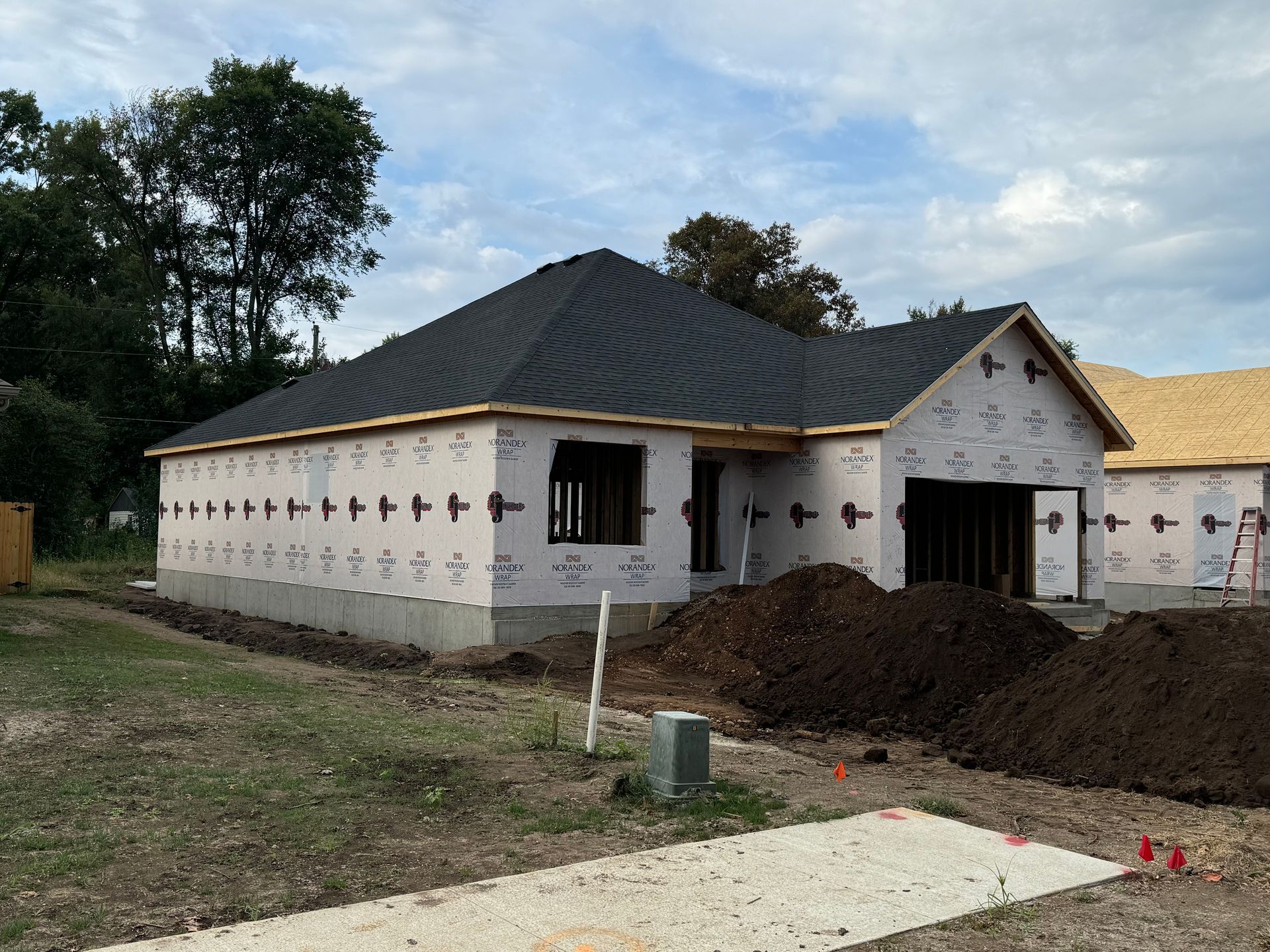 A house is being built with a large pile of dirt in front of it.