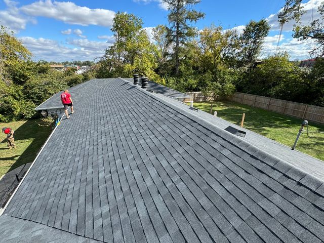 A group of people are working on the roof of a house.