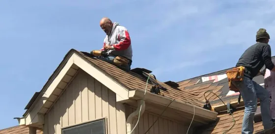 Two men are working on the roof of a house.