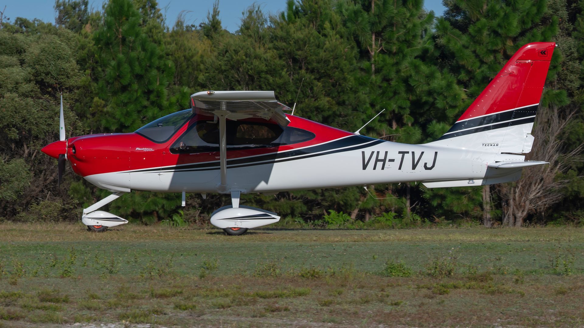A small red and white plane with the letters vh-tvj on the side