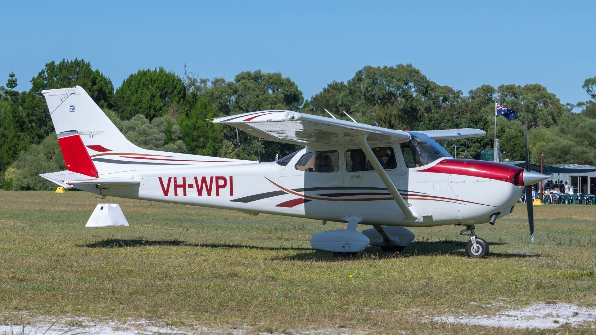 A small plane with the letters vh-wpi on the side is parked on a grassy field.