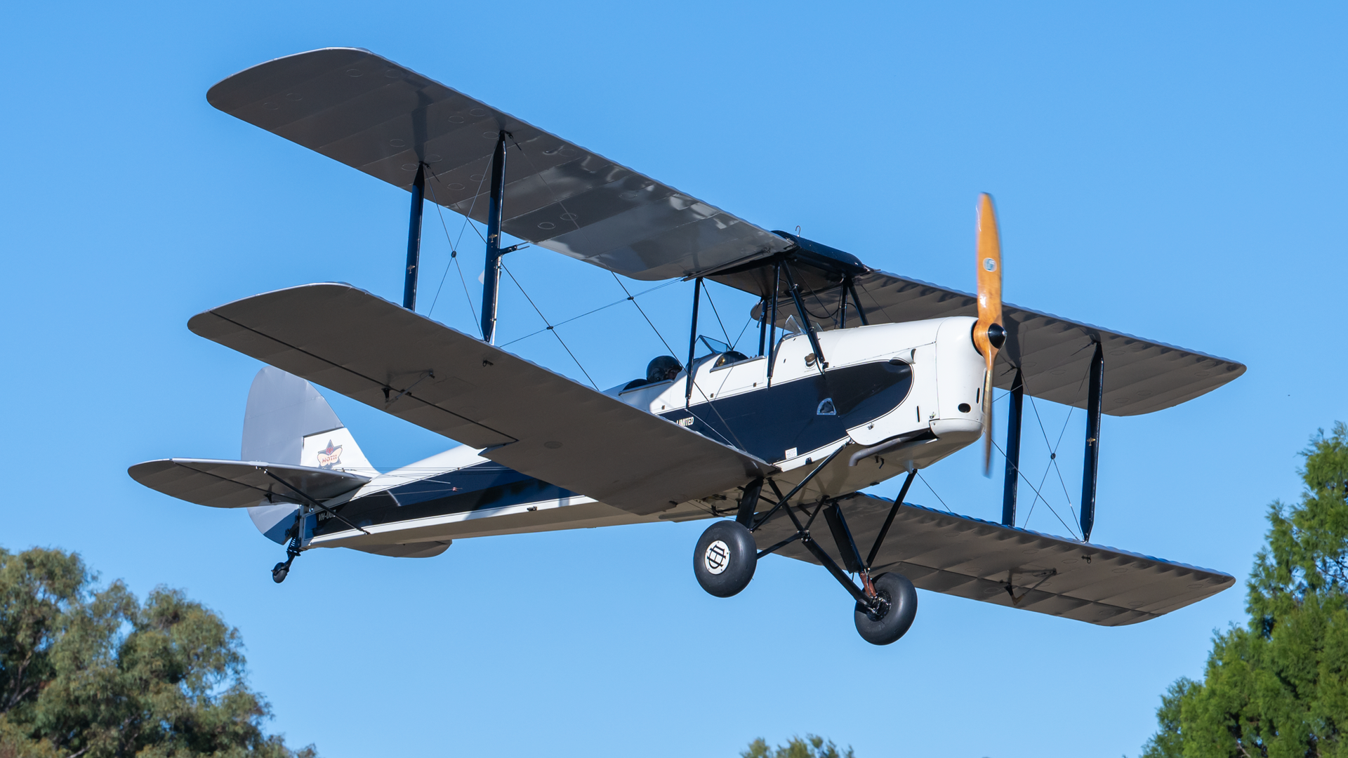 A black and white biplane is flying in the sky.