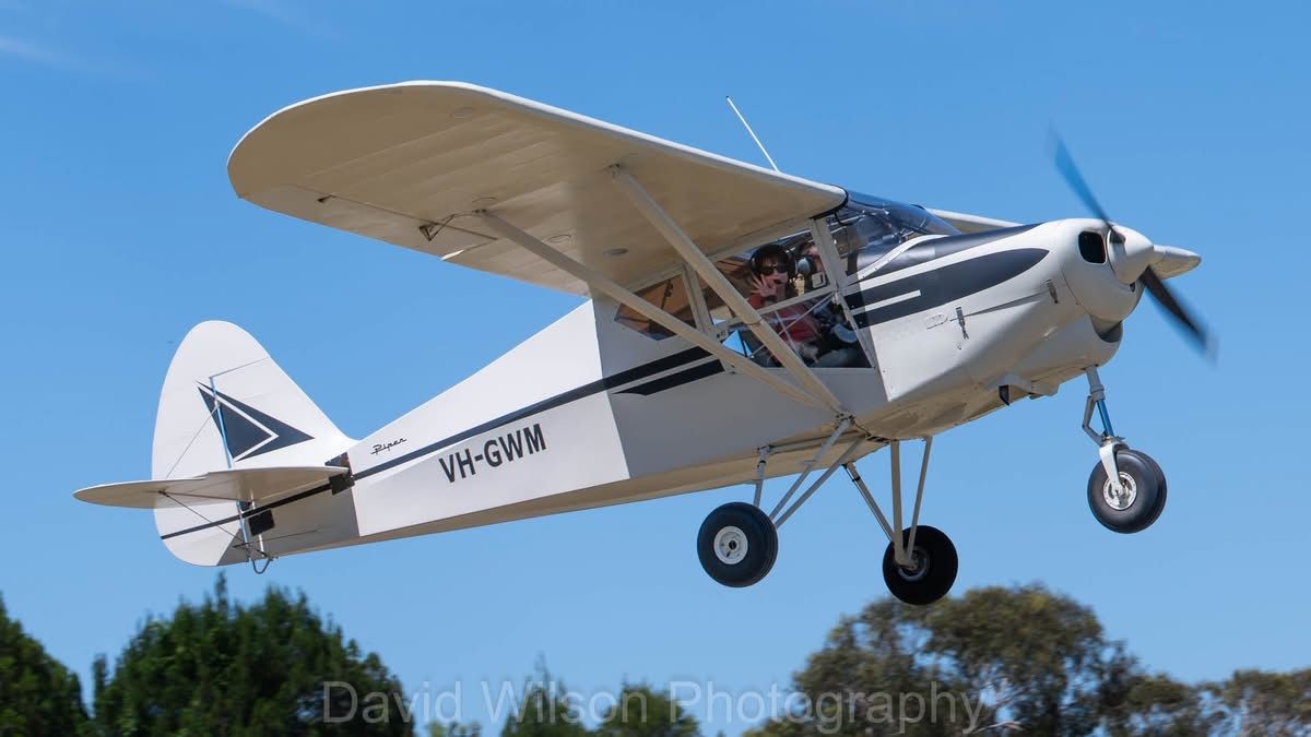 White and black single-engine aircraft in mid-air against a blue sky.
