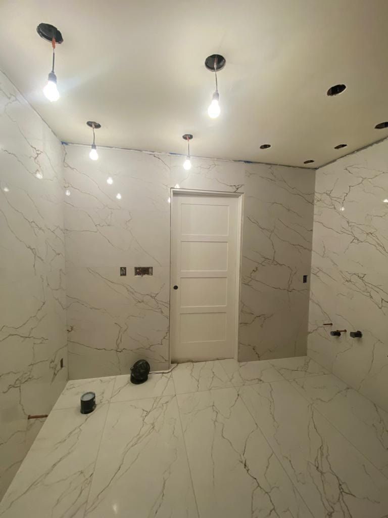 A bathroom under construction with white tiles and a door.