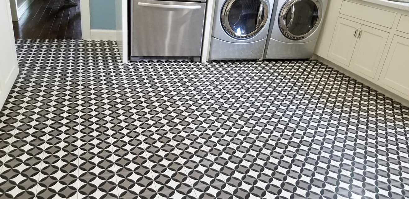 A laundry room with a black and white tile floor and a washer and dryer.