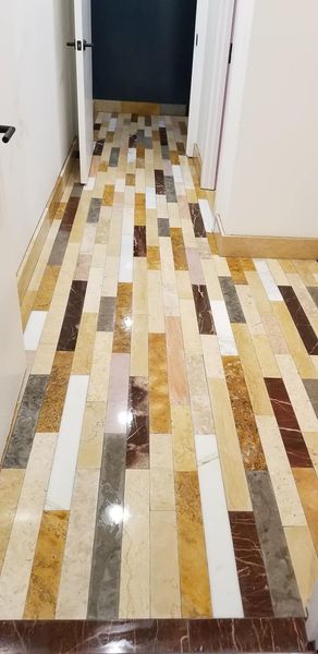A hallway with a colorful tile floor and a door.