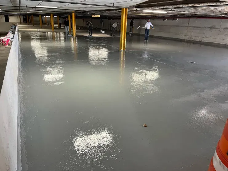 Flooded parking garage with shallow standing water and a few people in the distance