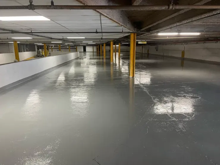Empty indoor parking garage with glossy gray floor and yellow support columns