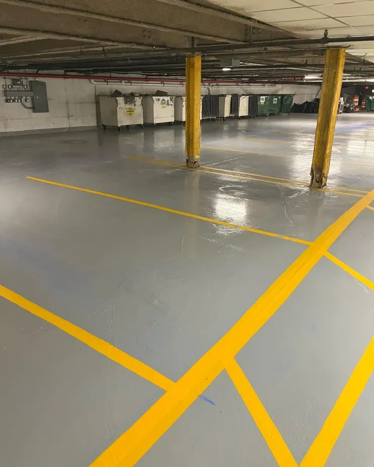 Empty parking garage with gray floor, yellow painted lines, and yellow support columns