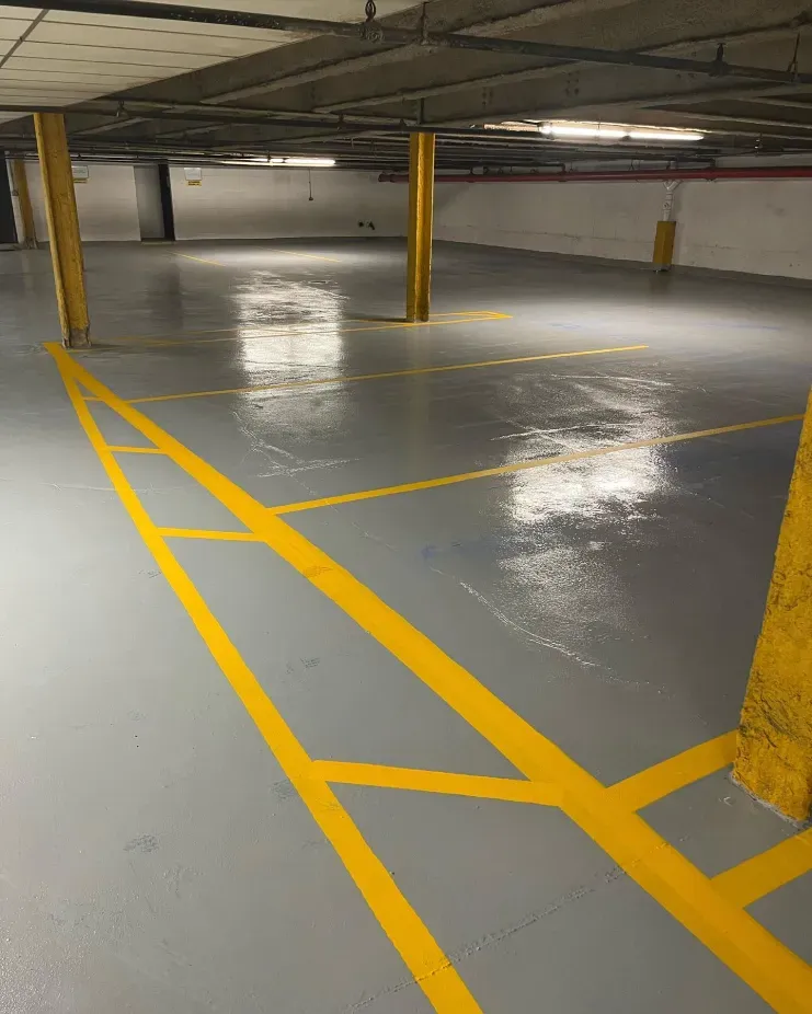 Empty parking garage with yellow painted lines and wet gray concrete floor