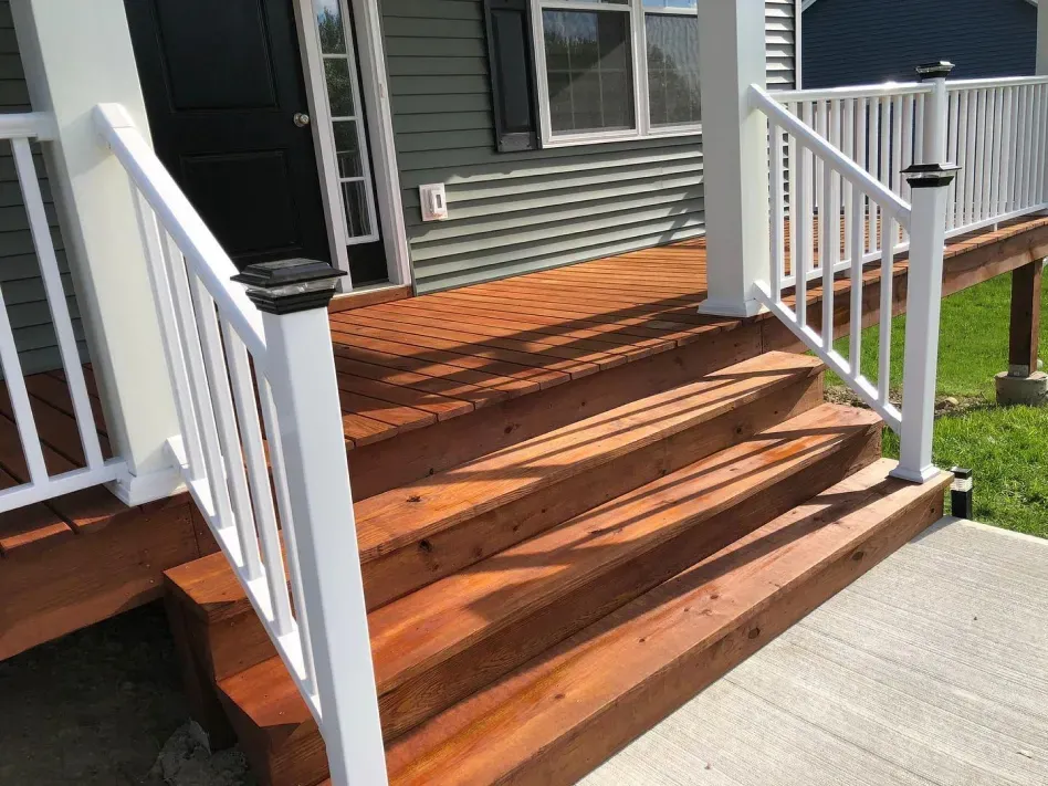Wooden front steps with white railings leading to a house porch