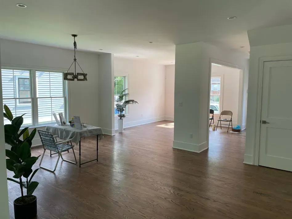 Bright open living and dining area with wood floors, white columns, and sliding glass doors
