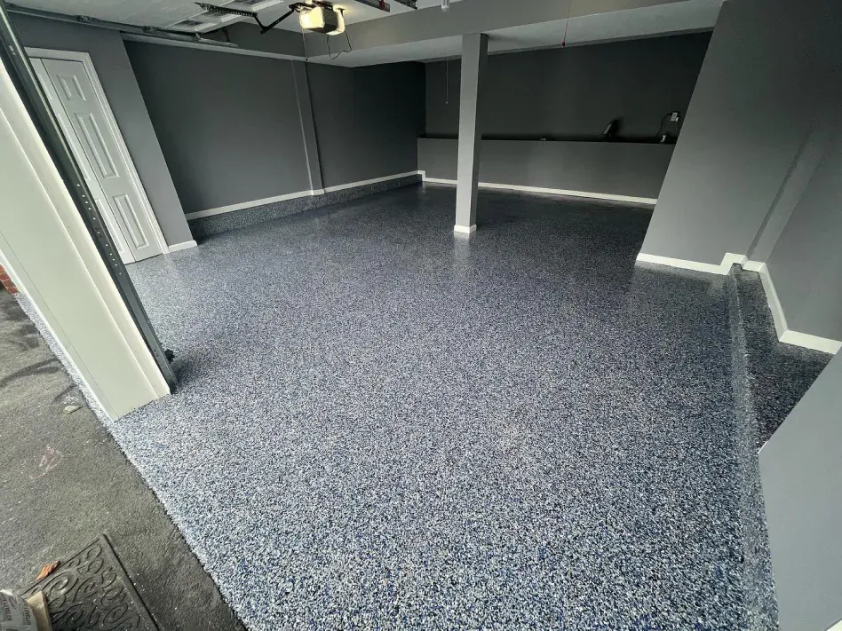 Empty gray carpeted room with white columns and dark walls, viewed from a doorway.