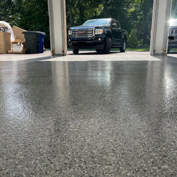 Black SUV parked in a driveway with trees in the background, viewed from a low angle over wet pavement
