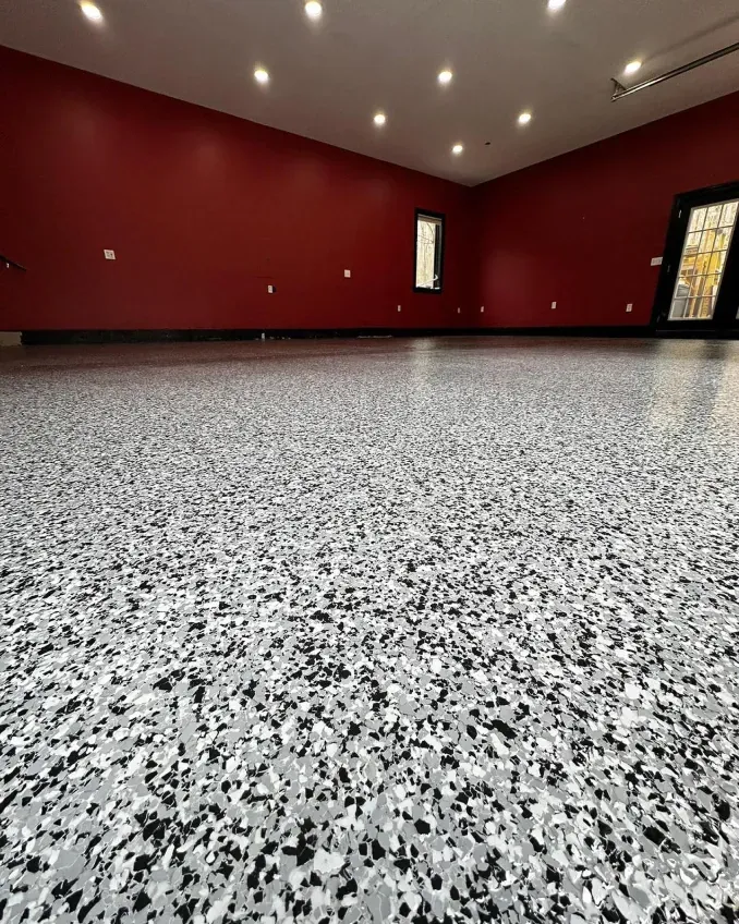Empty room with red walls, gray speckled floor, recessed ceiling lights, and a small window.