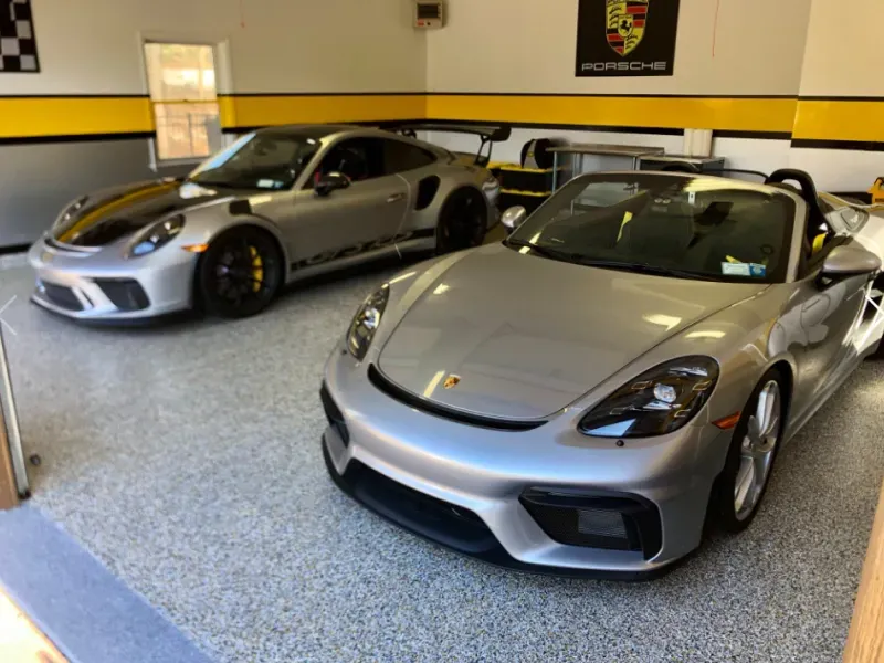 Two silver Porsche sports cars parked in a showroom, front car a convertible
