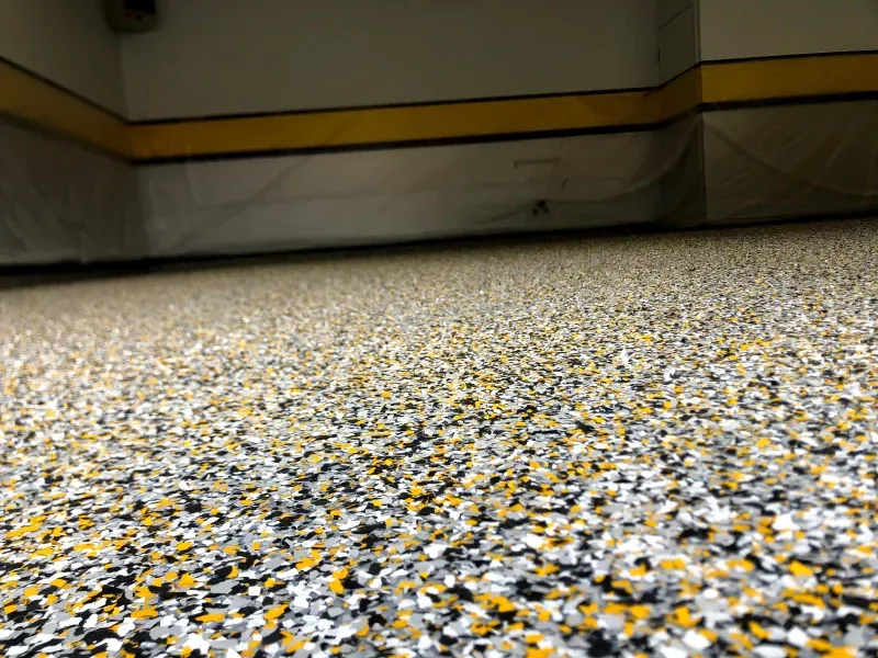 Speckled terrazzo floor beneath a yellow-and-black wall in an indoor room
