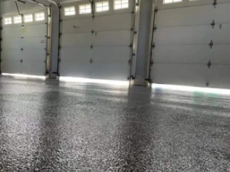 Empty garage interior with closed white doors and a speckled concrete floor