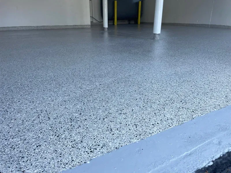Gray speckled indoor floor with white pillars and a raised edge in the foreground