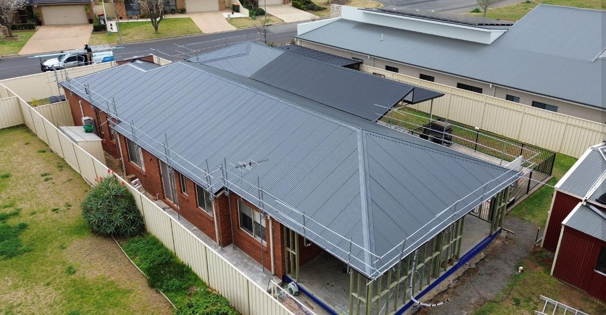 A House Under Construction With a Blue Roof and a white Fence — Essential Roofing and Plumbing in Temora, NSW