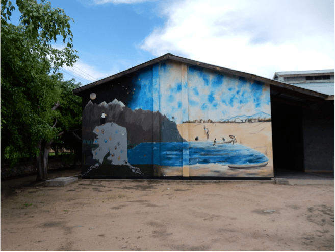 Blue whale-like scene painted on a wall at Gracious by classmates with blue & white sky.