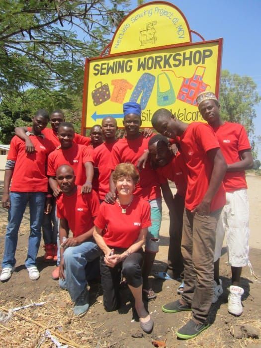Nettie, Ayami, and the MCV Sewing Project team standing in front of the new roadside sign in Malawi
