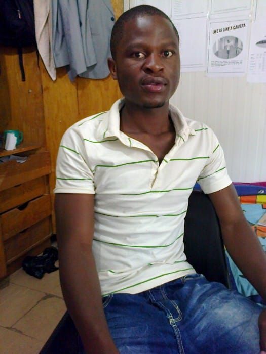 Picture of Ellaton Siyabu at the university in his dorm room, sitting on his bed.