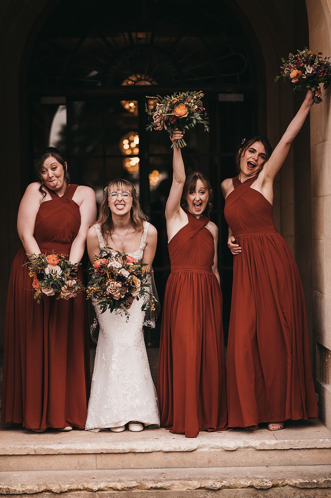 A bride and her bridesmaids are posing for a picture in front of a building.