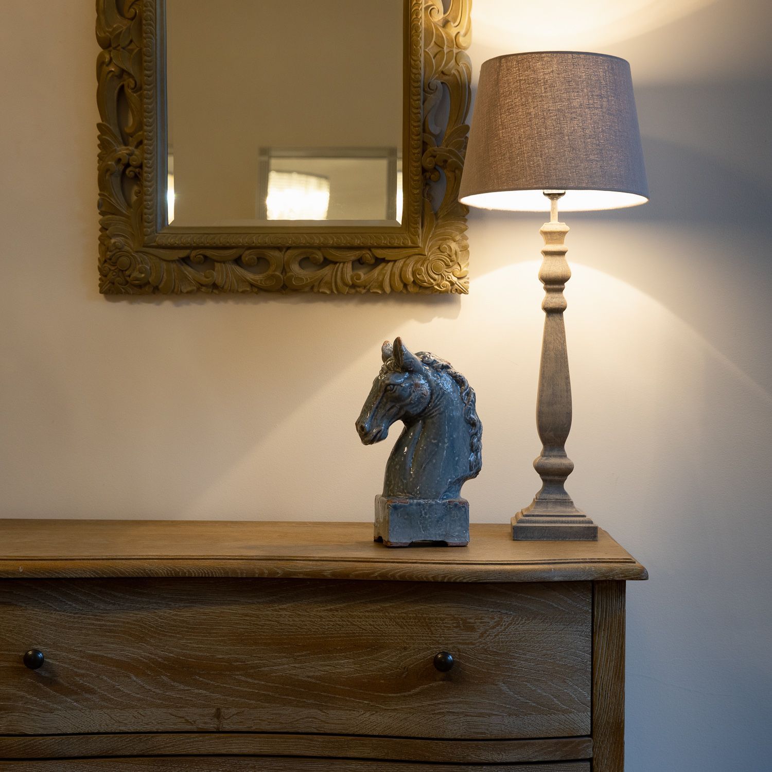 A lamp and a statue of a horse on a dresser