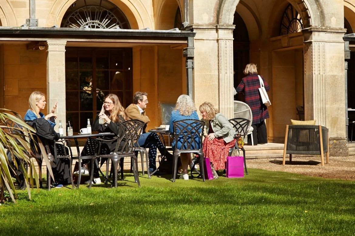 A group of people are sitting at tables outside of a building.