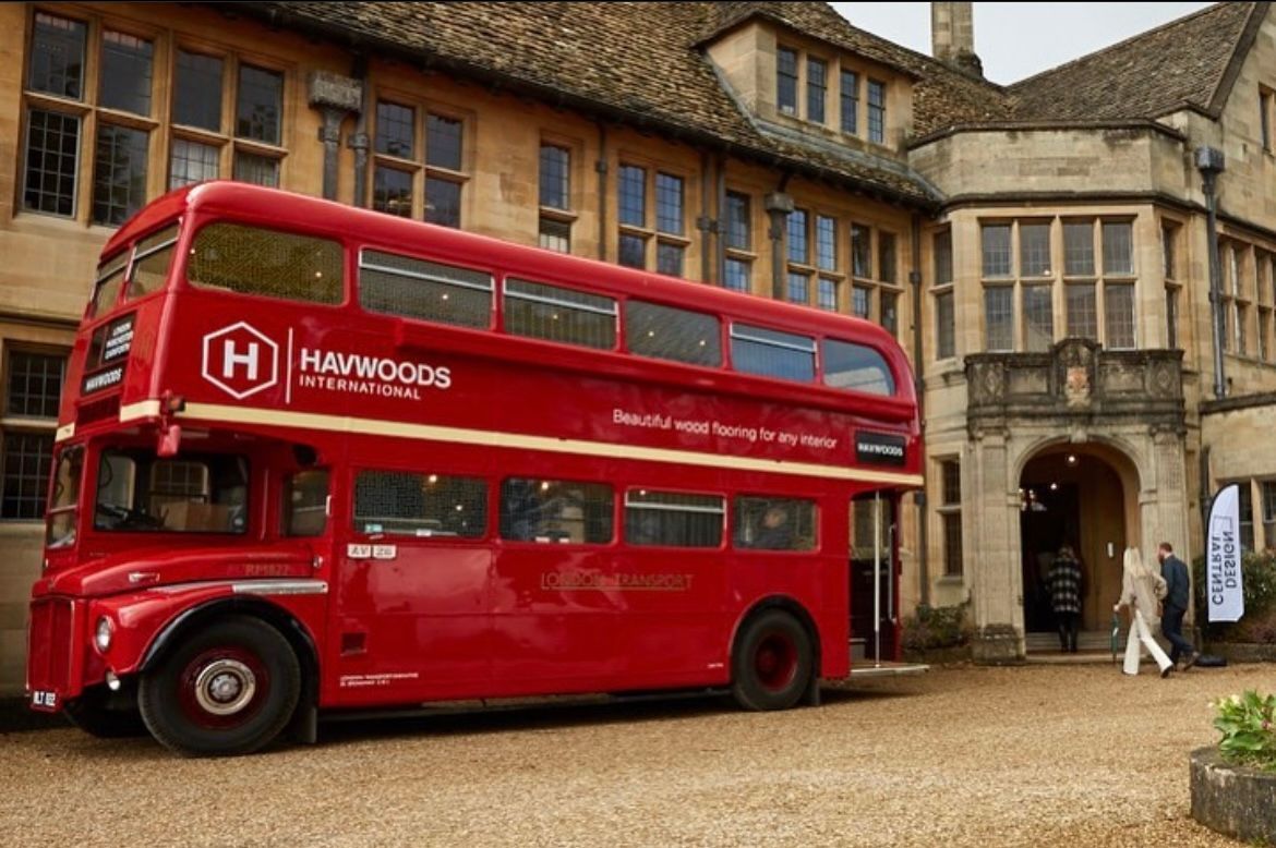A red double decker bus is parked in front of a building.