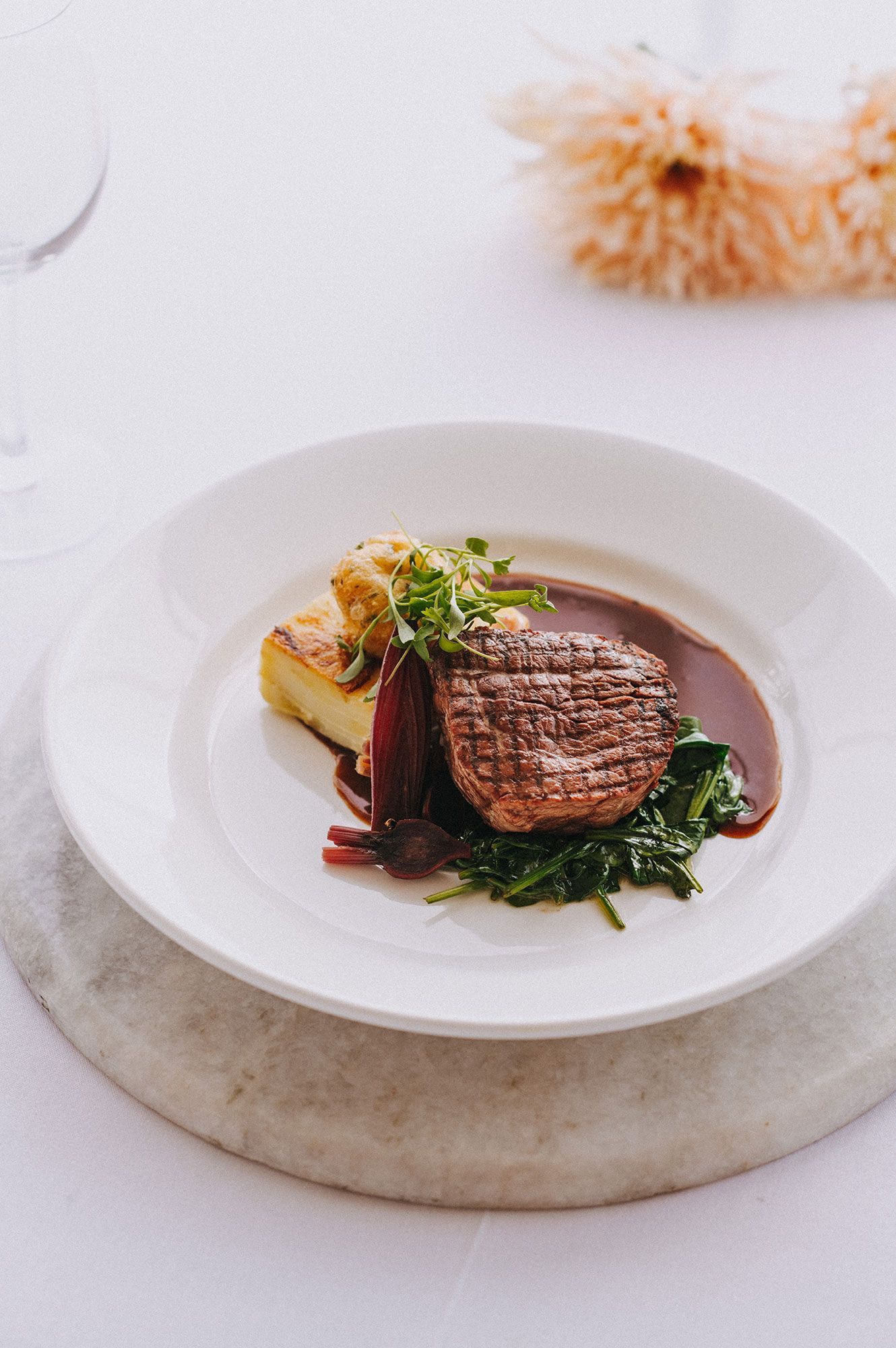 A white plate topped with a steak and vegetables on a table.