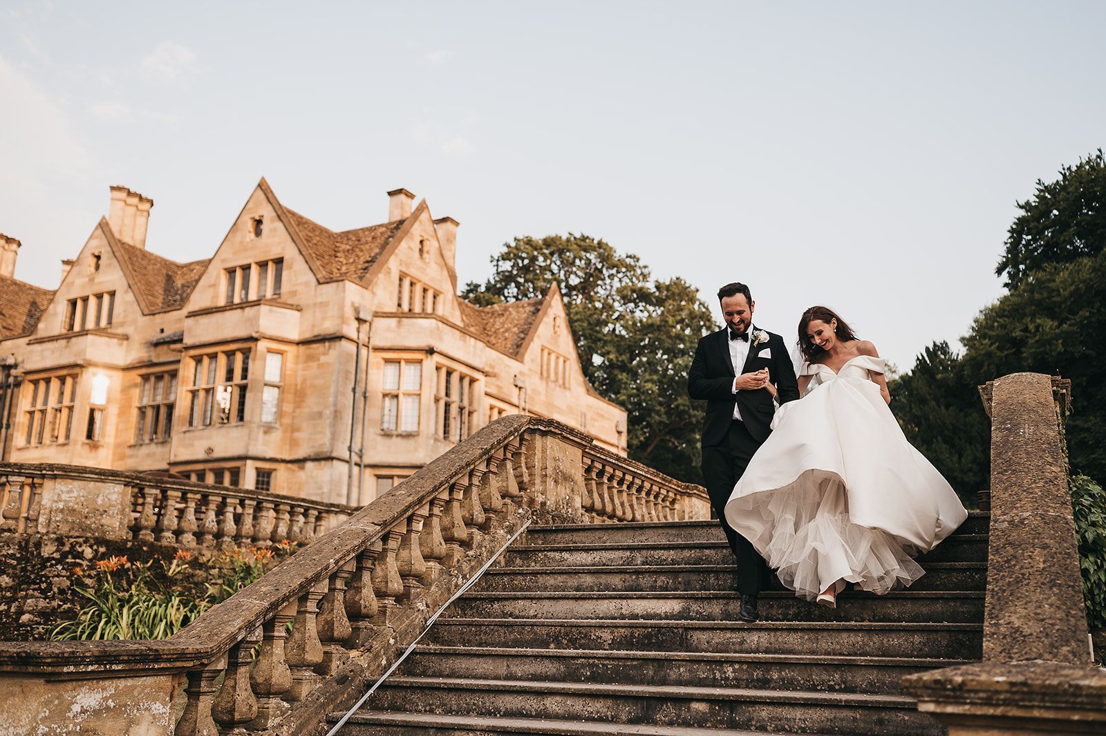 A bride and groom are walking down a set of stairs in front of a large building.