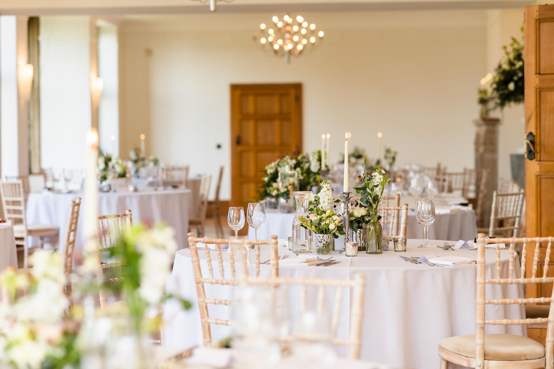 A room filled with tables and chairs set up for a wedding reception.