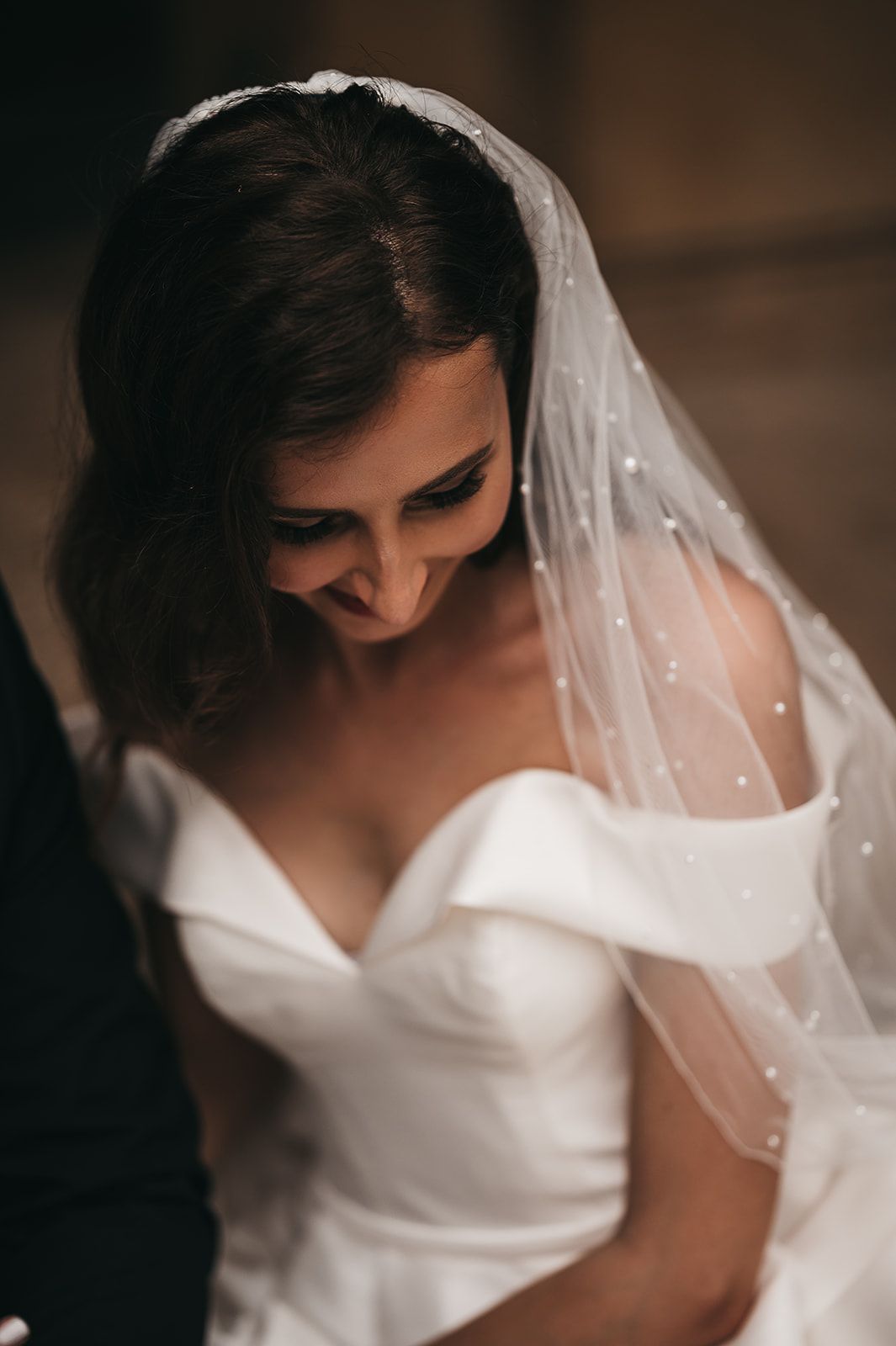 A bride in a white wedding dress and veil is sitting next to a groom.