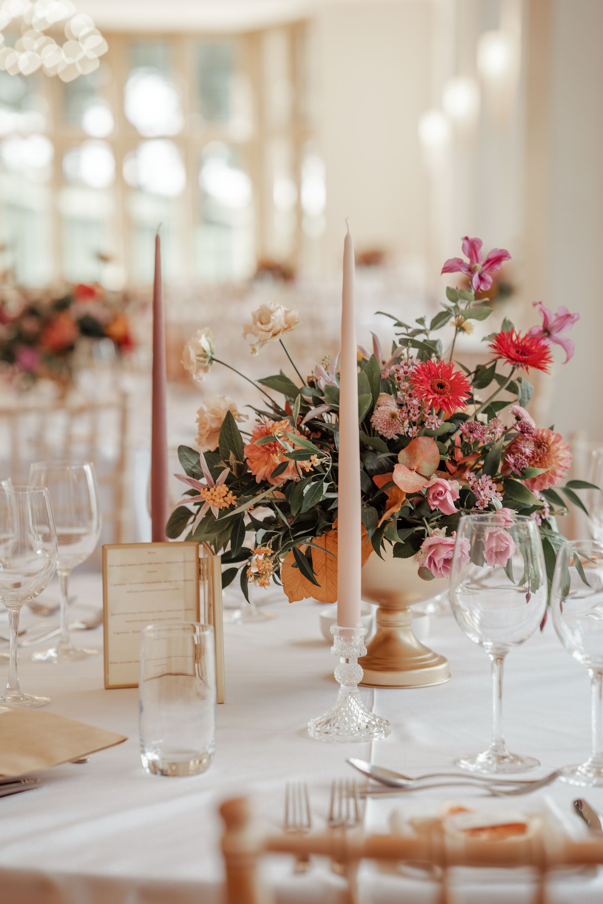 A table with a vase of flowers and candles on it.