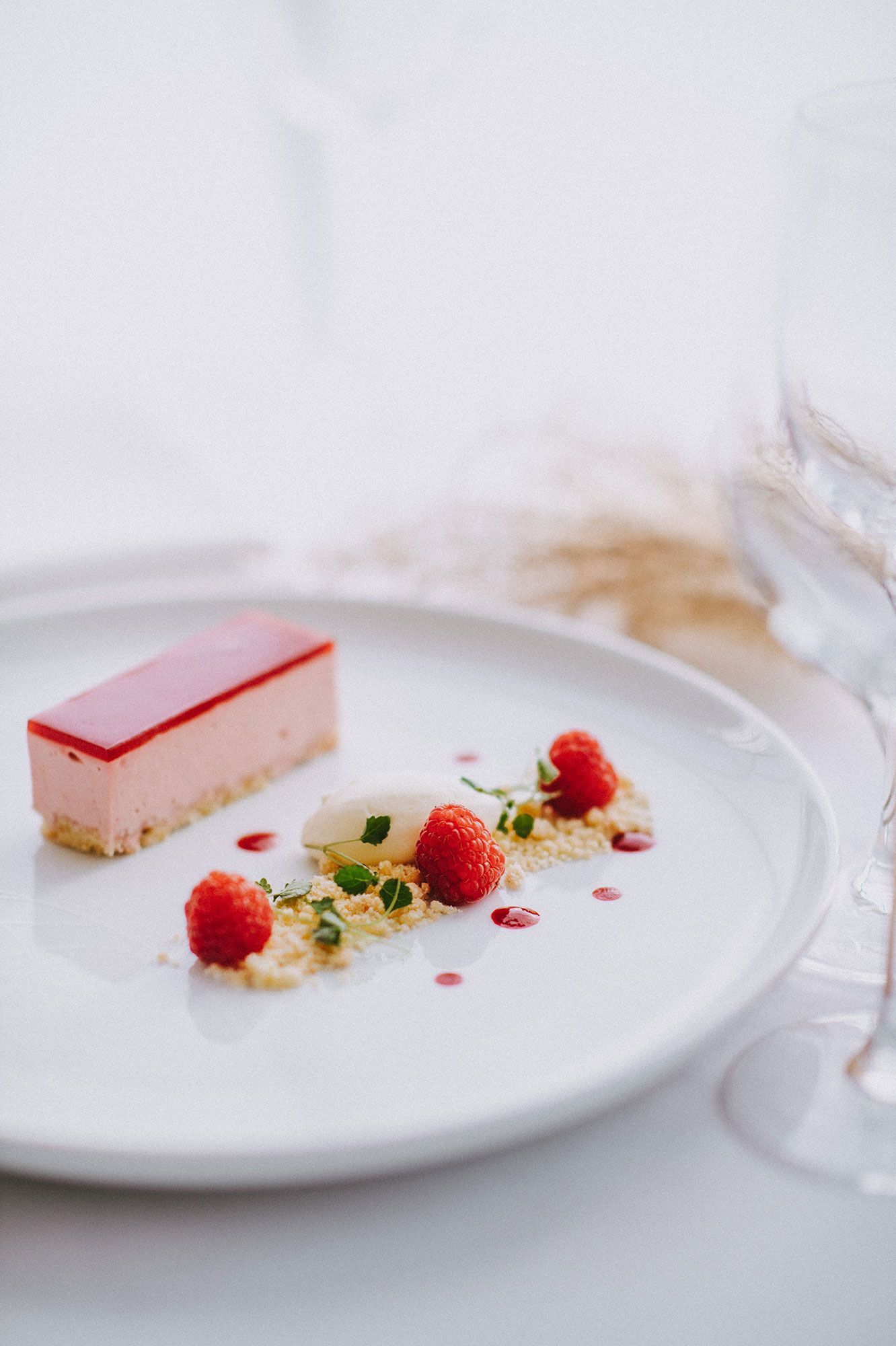 A white plate topped with a piece of cake and raspberries.