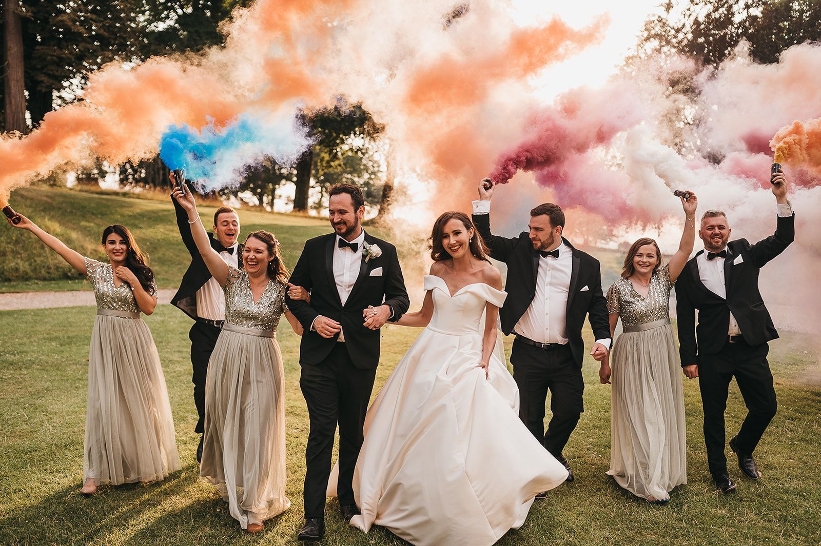 Bride and groom throwing colour dust into the air with guests