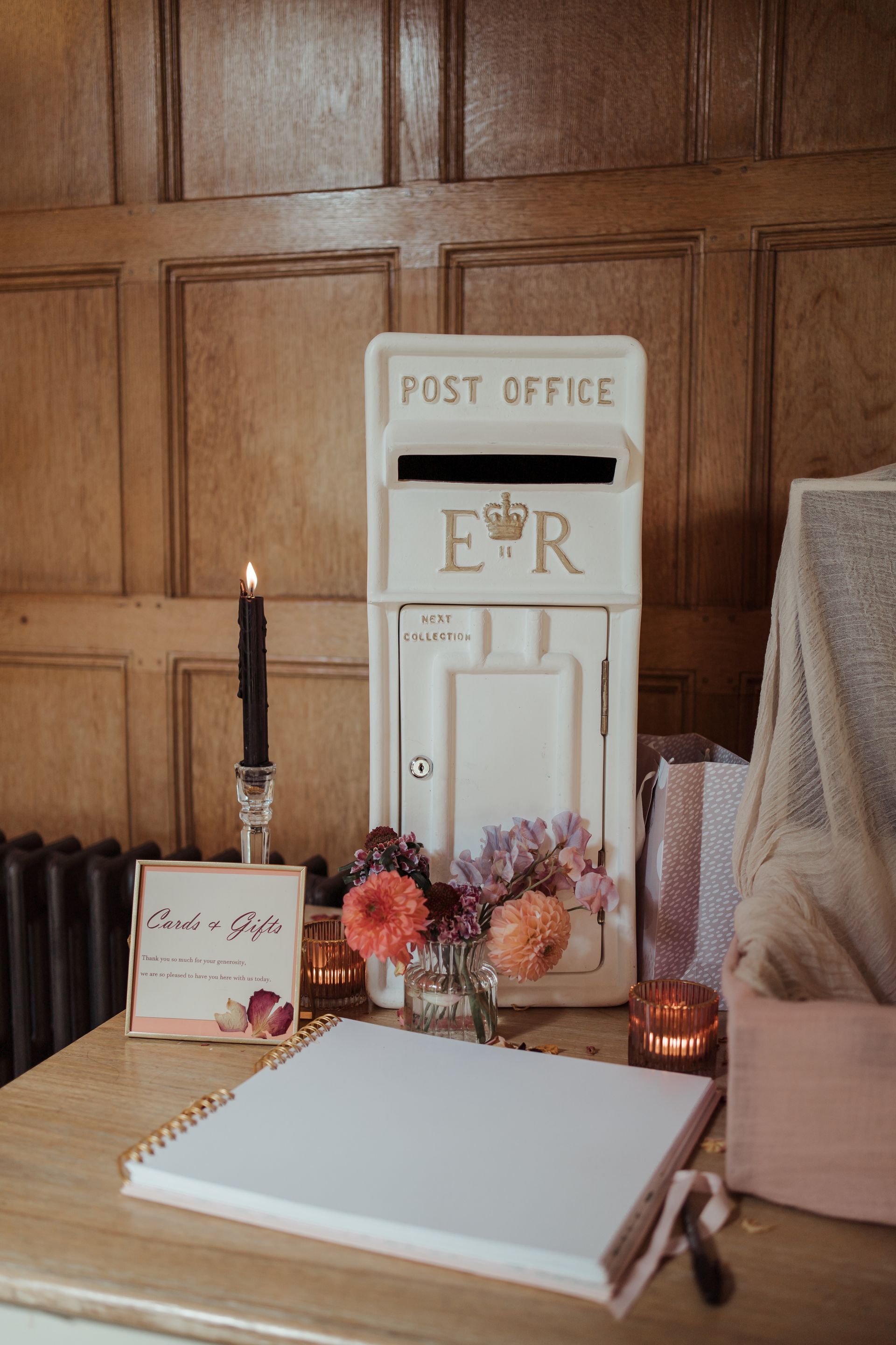 A white post office box is sitting on top of a wooden table.