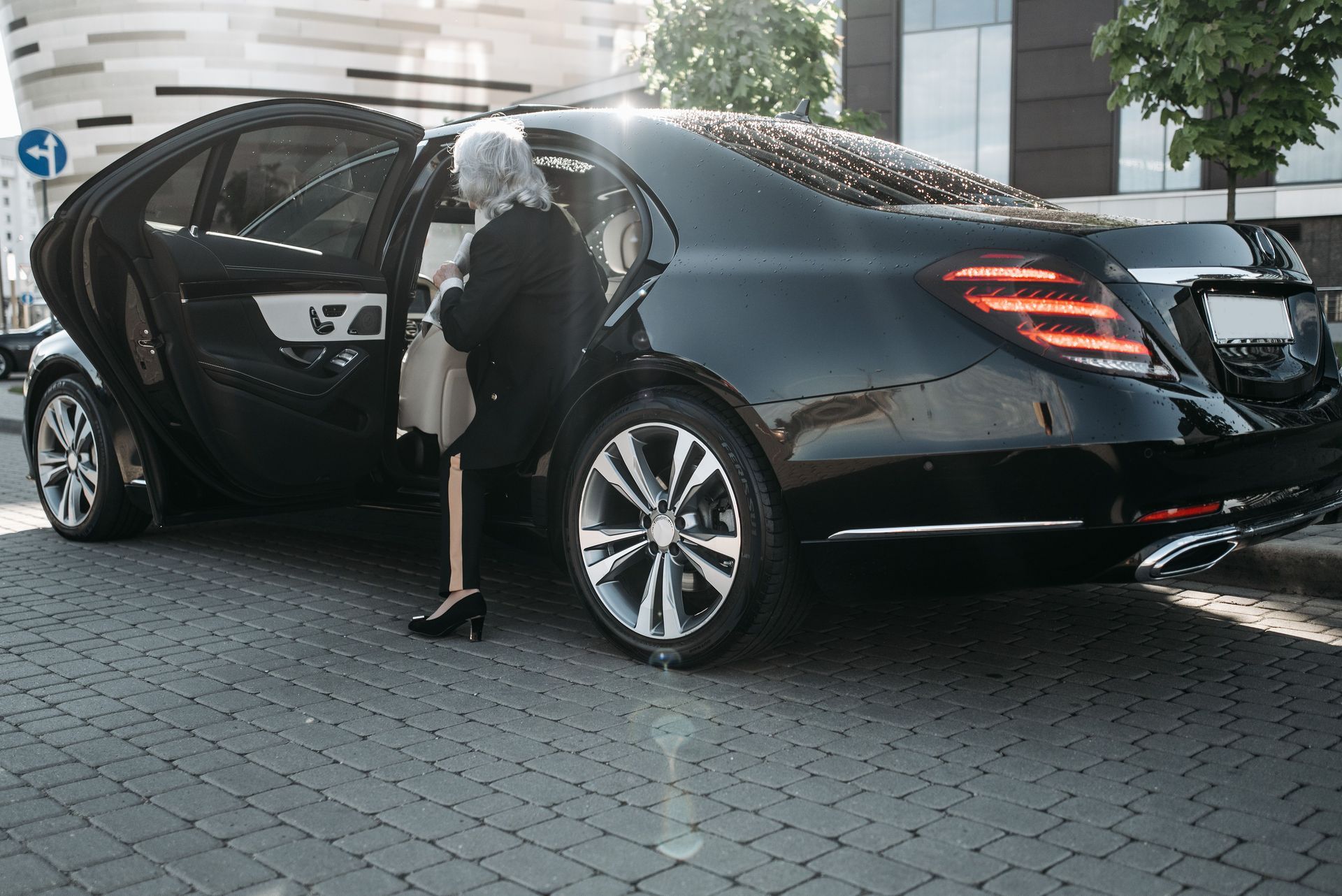 Woman stepping out of a black sedan in front of a modern building