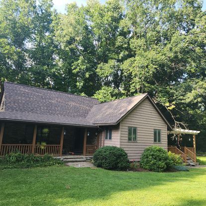 A house with a porch and trees in the background