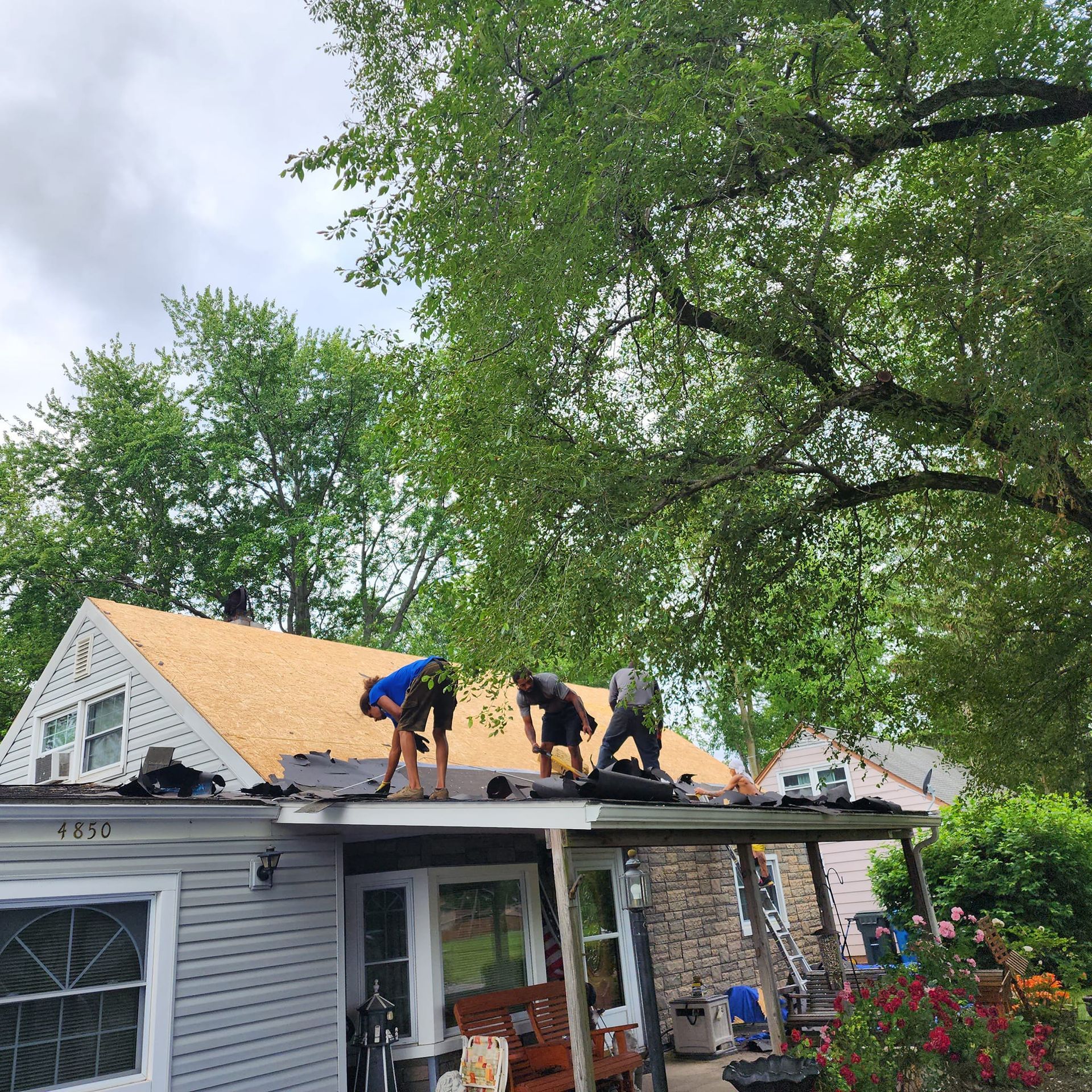 Two men are working on the roof of a house.