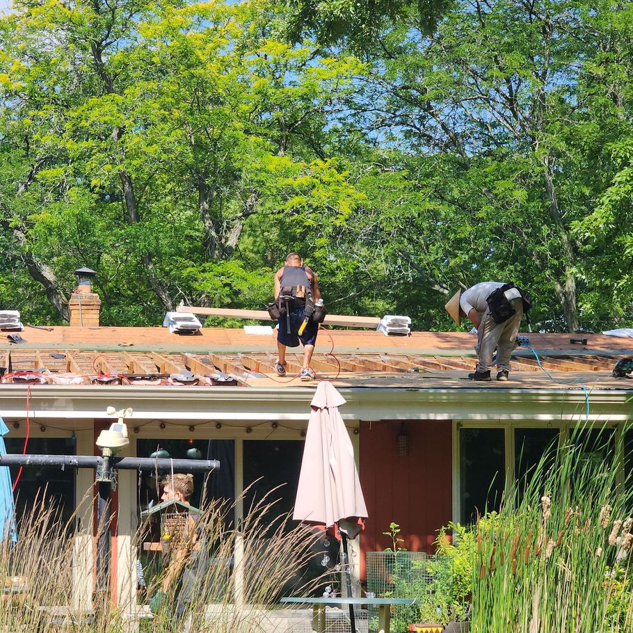 Two men are working on the roof of a house.