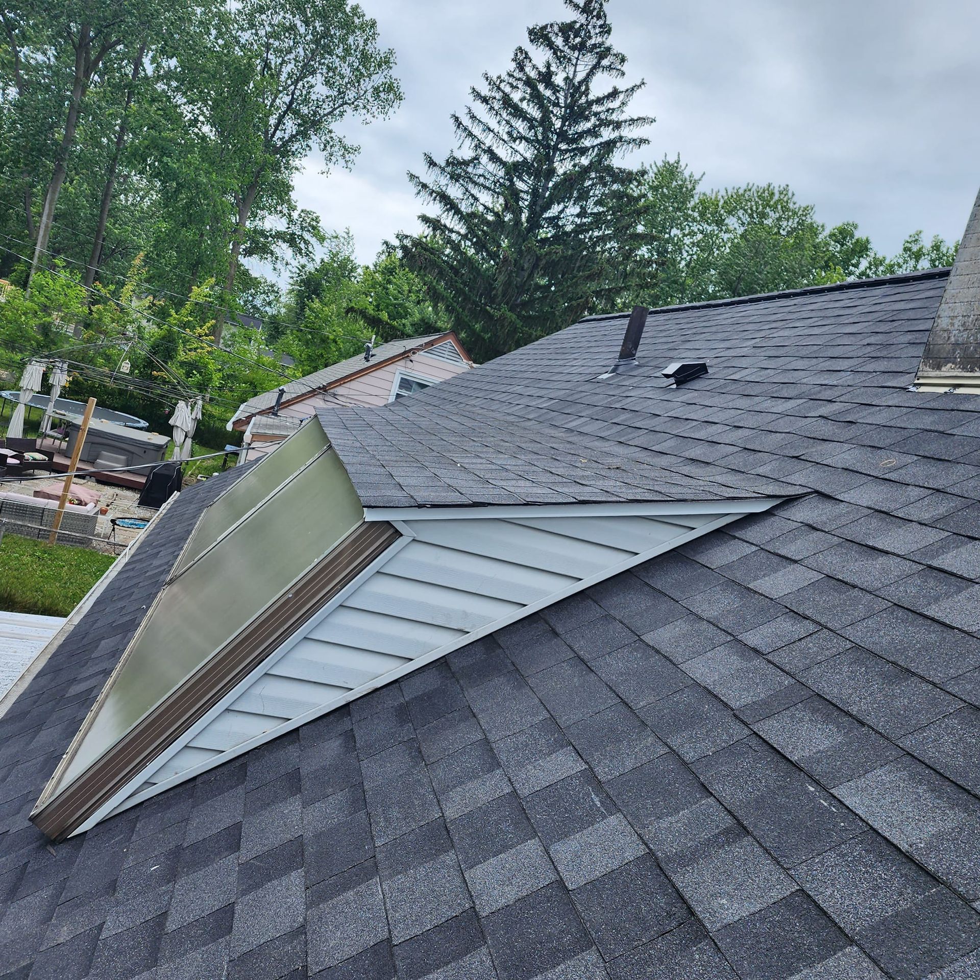 A roof with a skylight on it and trees in the background.