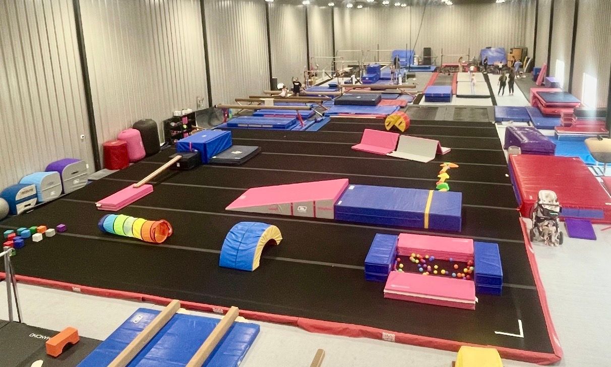 Gymnasium with various colorful mats, ramps, and equipment, likely for children's activities.